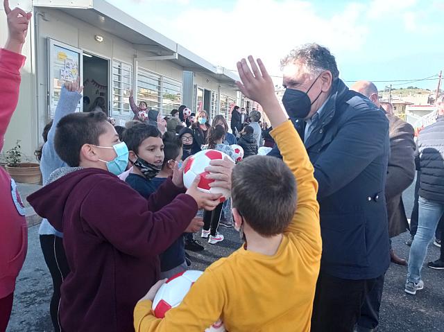 Ο δήμαρχος Μανώλης Φραγκάκης δίνει μπάλες του Ολυμπιακούς στα μικρά παιδιά.