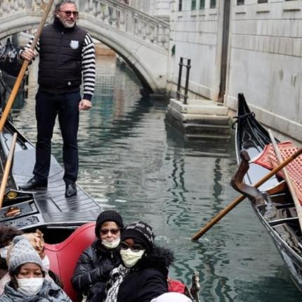 Τουρίστες με μάσκες, απολαμβάνουν τη βόλτα τους σε κανάλι της Βενετίας.