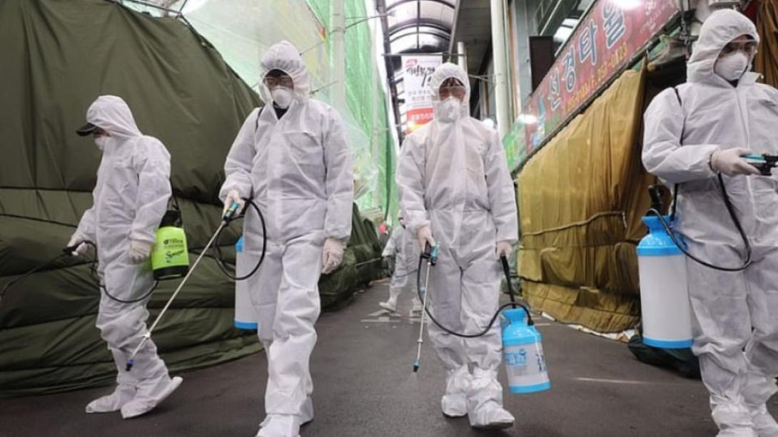 Νότια Κορέα. Το προσωπικό φορώντας ειδικές στολές, ψεκάζει με απολυμαντικά υπαίθρια αγορά...